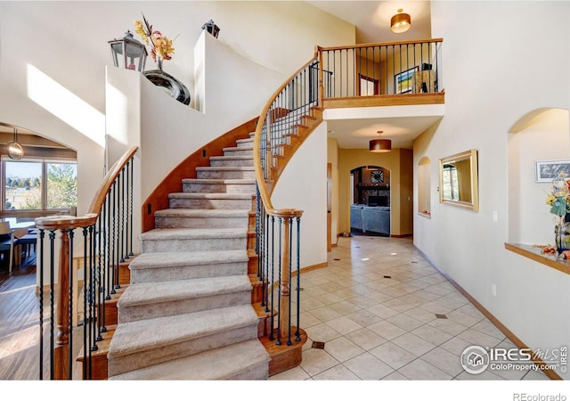 stairs with tile patterned floors and a towering ceiling