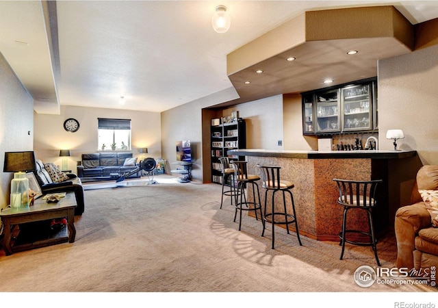 kitchen featuring kitchen peninsula, a kitchen breakfast bar, and light colored carpet