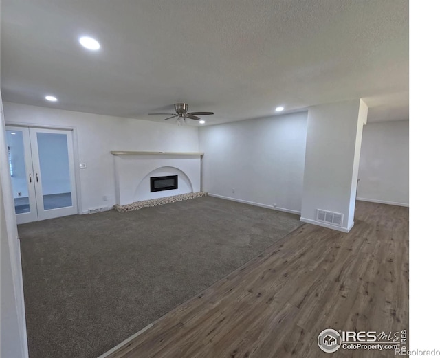 unfurnished living room with dark hardwood / wood-style floors, a textured ceiling, french doors, and ceiling fan