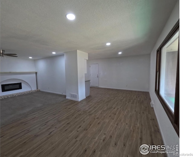 unfurnished living room with dark wood-type flooring, ceiling fan, and a textured ceiling