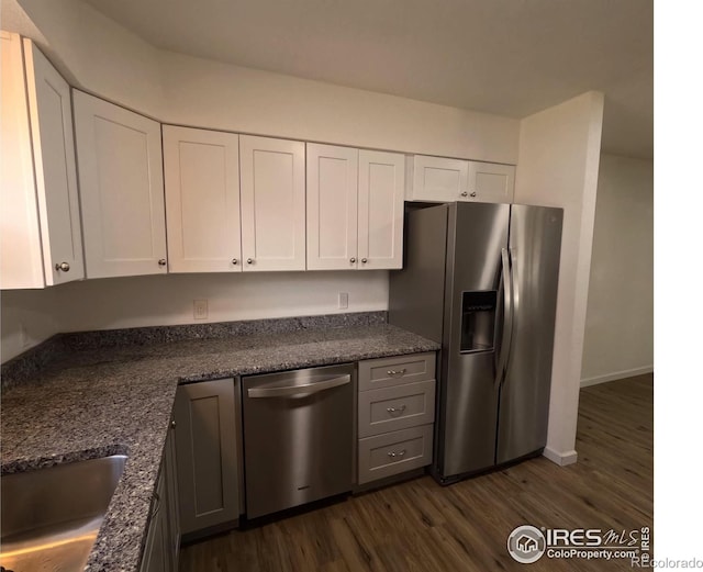 kitchen with white cabinetry, dark wood-type flooring, dark stone countertops, and appliances with stainless steel finishes