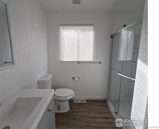 bathroom featuring vanity, toilet, a shower with shower door, and hardwood / wood-style floors