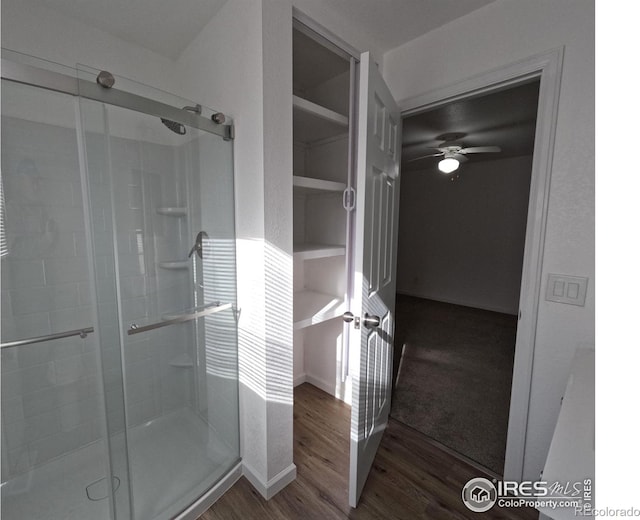 bathroom featuring ceiling fan, wood-type flooring, and a shower with door