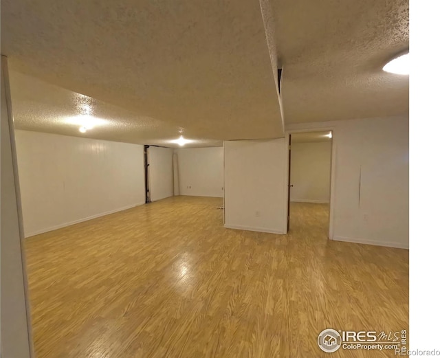 basement with a textured ceiling and light hardwood / wood-style flooring