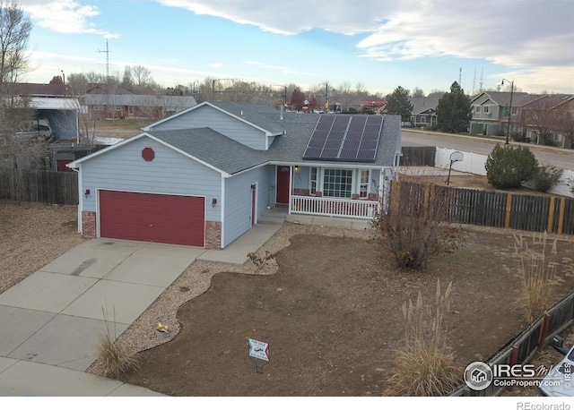 ranch-style home featuring a porch, a garage, and solar panels