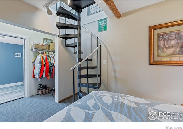 bedroom with beamed ceiling, carpet floors, and a closet