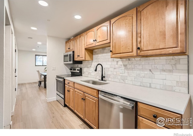 kitchen featuring decorative backsplash, sink, stainless steel appliances, and light hardwood / wood-style floors