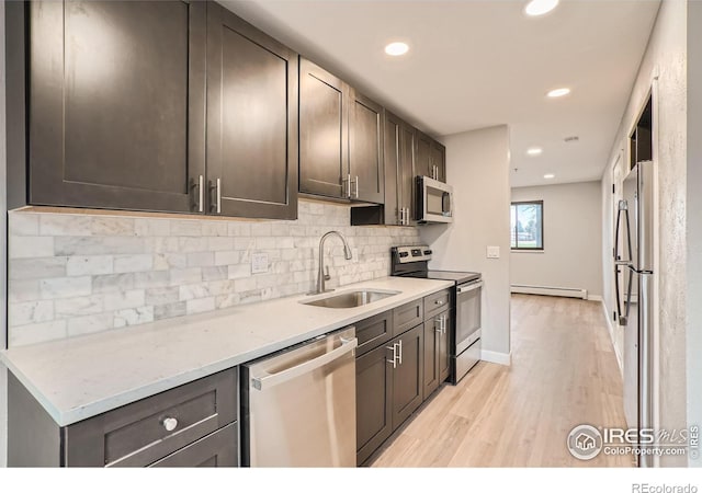 kitchen featuring light stone counters, stainless steel appliances, sink, a baseboard radiator, and light hardwood / wood-style flooring