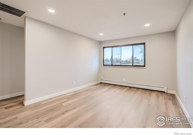 spare room featuring a baseboard radiator and light hardwood / wood-style floors