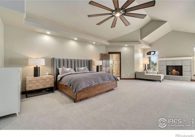 carpeted bedroom with a tiled fireplace, ceiling fan, and lofted ceiling