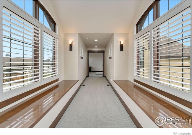 hallway featuring a wealth of natural light and light carpet