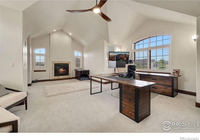 carpeted office with high vaulted ceiling, ceiling fan, and a tile fireplace