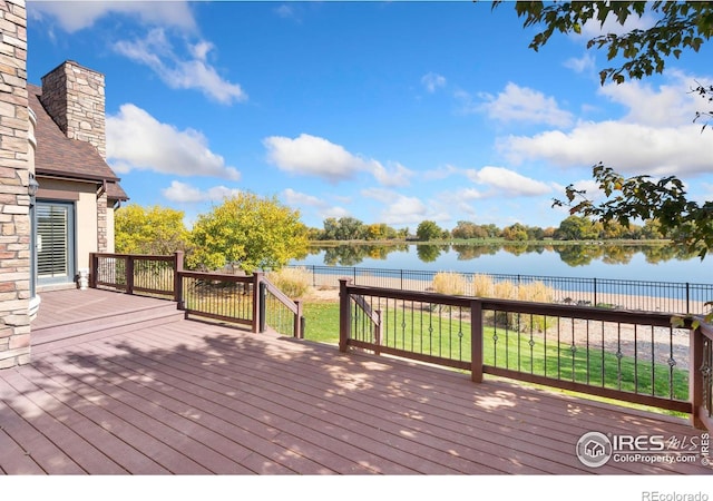 wooden deck featuring a water view and a lawn