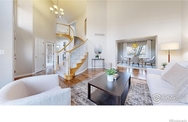 living room featuring a chandelier, a towering ceiling, and hardwood / wood-style flooring