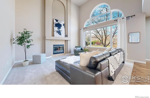 living room with a tile fireplace, light hardwood / wood-style flooring, and high vaulted ceiling