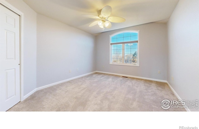 carpeted spare room featuring ceiling fan