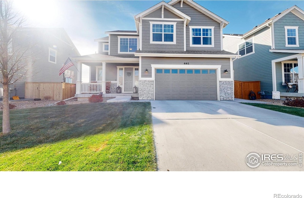 view of front of property featuring a front yard, a garage, and covered porch