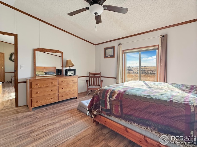 bedroom with ceiling fan, crown molding, wood-type flooring, vaulted ceiling, and a textured ceiling