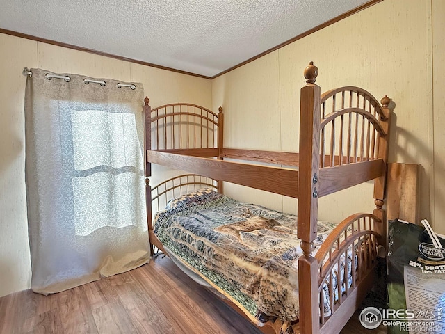 bedroom with hardwood / wood-style floors, a textured ceiling, and crown molding