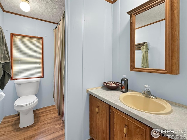 bathroom featuring vanity, hardwood / wood-style flooring, toilet, ornamental molding, and a textured ceiling