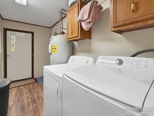 washroom with cabinets, water heater, light hardwood / wood-style flooring, independent washer and dryer, and a textured ceiling