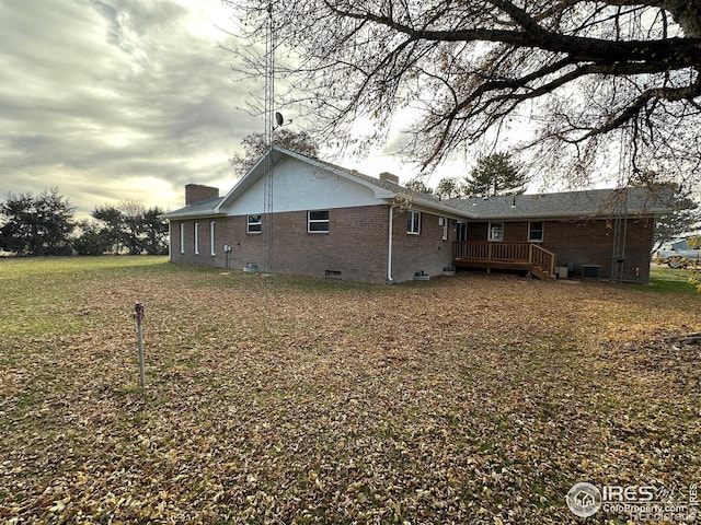 rear view of property featuring brick siding, crawl space, a chimney, and a wooden deck