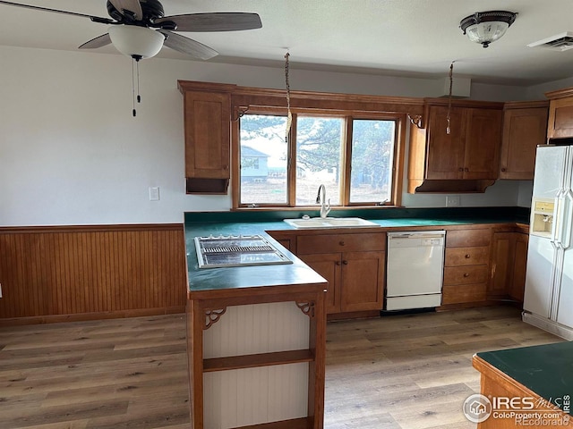 kitchen with a wainscoted wall, visible vents, light wood-style floors, a sink, and white appliances