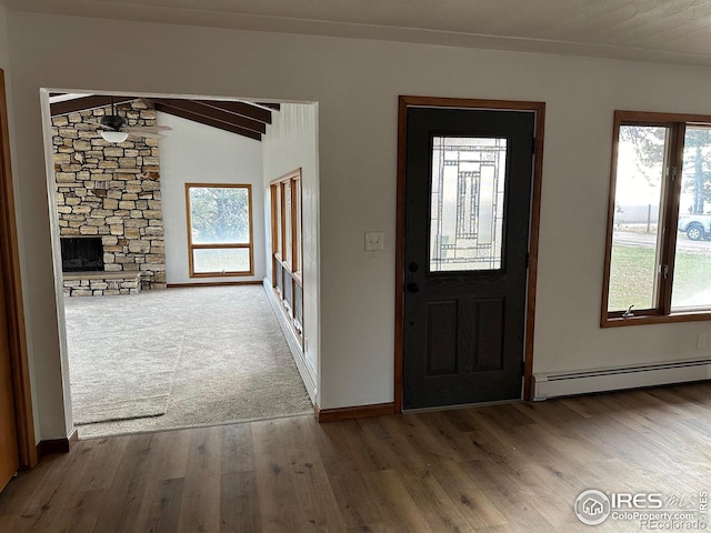 foyer entrance with a baseboard radiator, vaulted ceiling with beams, baseboards, and wood finished floors