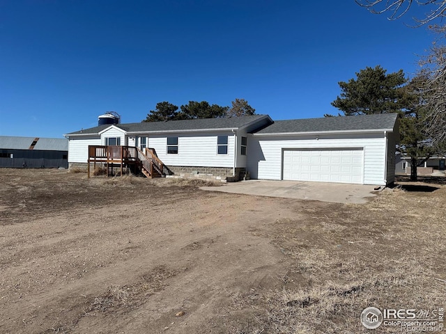 view of front of property with an attached garage, a deck, and dirt driveway