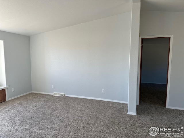 empty room featuring dark colored carpet, visible vents, and baseboards