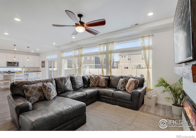 living room with ceiling fan and light wood-type flooring