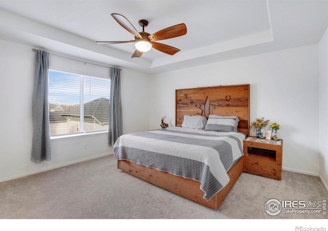 bedroom with a tray ceiling, ceiling fan, and light colored carpet