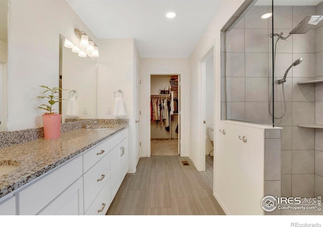 bathroom featuring vanity, toilet, and tiled shower