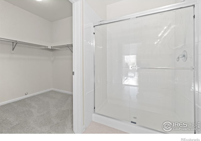 full bath featuring a spacious closet, a shower stall, and baseboards