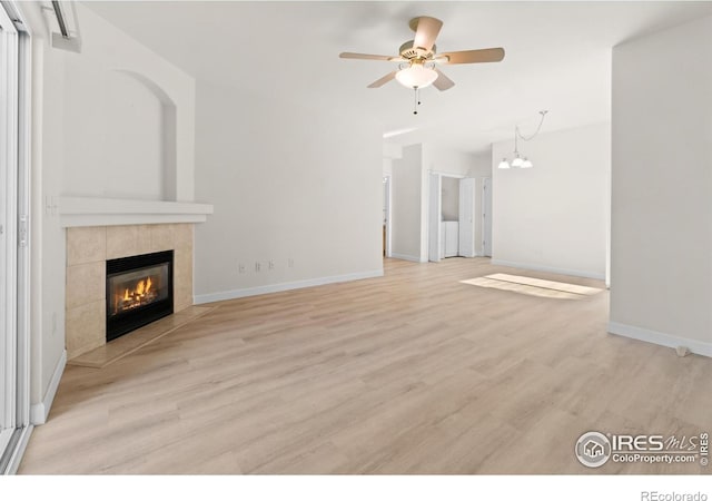 unfurnished living room with a ceiling fan, baseboards, a tiled fireplace, and wood finished floors