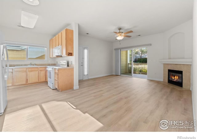 kitchen with light countertops, light brown cabinetry, light wood-style floors, white appliances, and baseboards