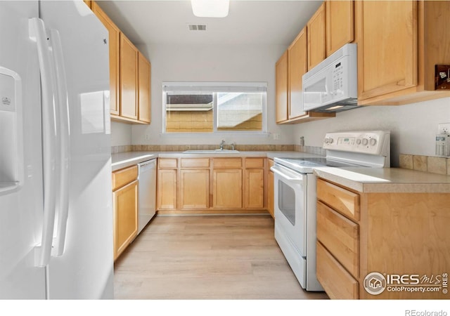 kitchen with light brown cabinets, white appliances, a sink, visible vents, and light countertops