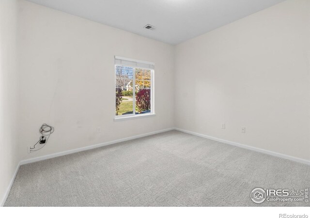 spare room featuring carpet floors, visible vents, and baseboards