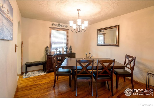 dining room with hardwood / wood-style floors, a textured ceiling, and a notable chandelier