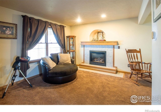 living area with a tile fireplace and carpet floors