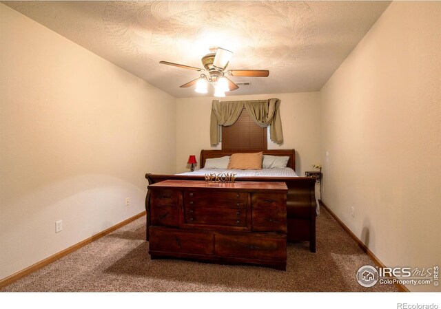 bedroom with ceiling fan, dark carpet, and a textured ceiling