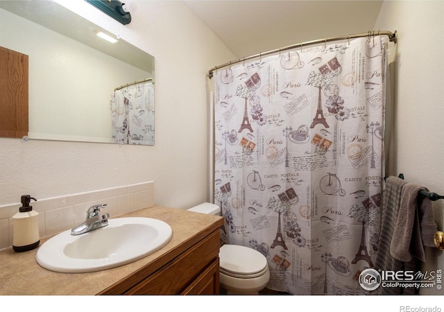 bathroom featuring decorative backsplash, vanity, toilet, and curtained shower