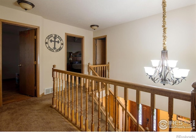 hallway with carpet and an inviting chandelier