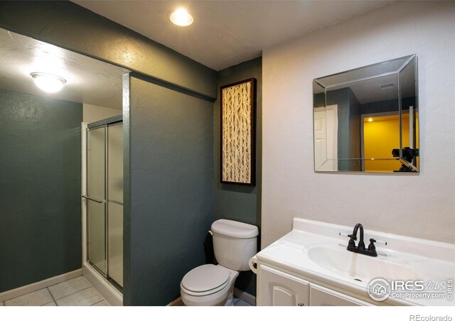 bathroom with tile patterned floors, vanity, toilet, and walk in shower