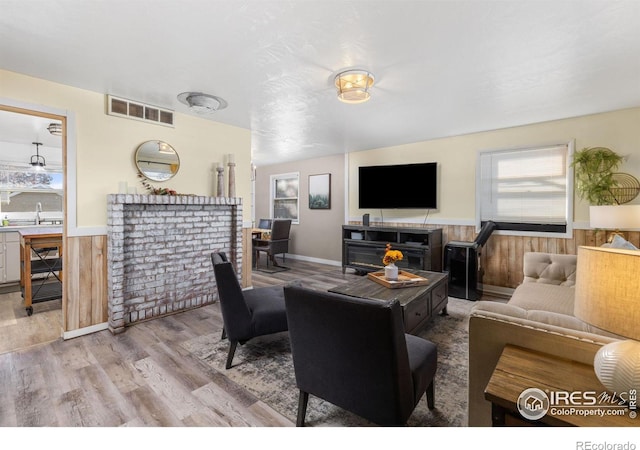 living room with wood walls, a healthy amount of sunlight, and light hardwood / wood-style flooring