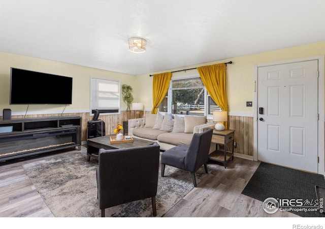 living room featuring hardwood / wood-style floors, wood walls, and a wood stove