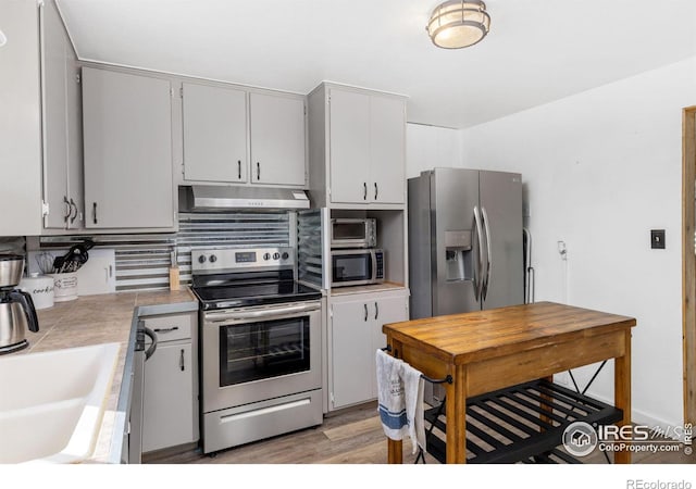 kitchen featuring tasteful backsplash, stainless steel appliances, sink, white cabinets, and light hardwood / wood-style floors