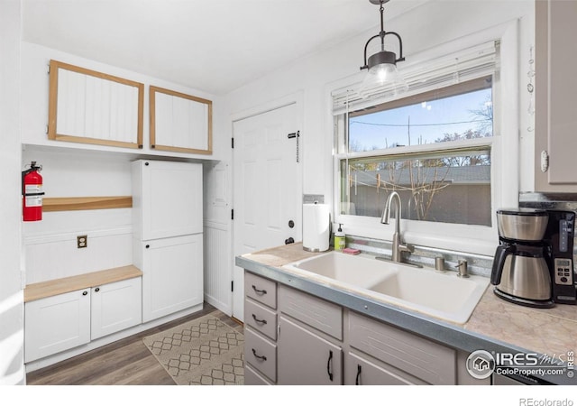 kitchen with white cabinets, pendant lighting, dark wood-type flooring, and sink