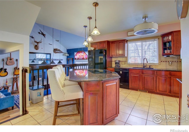 kitchen featuring black appliances, a kitchen breakfast bar, sink, tasteful backsplash, and a kitchen island