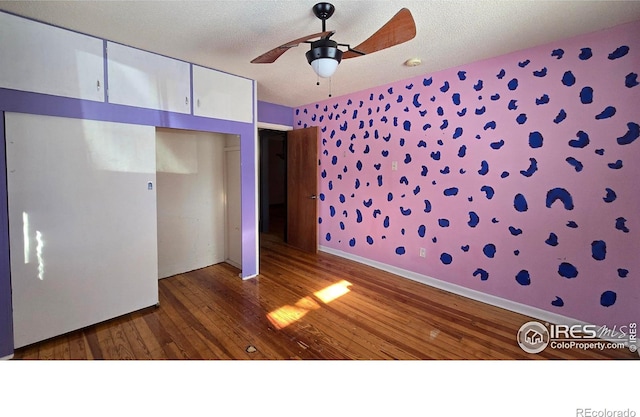 unfurnished bedroom with ceiling fan, dark hardwood / wood-style flooring, a closet, and a textured ceiling